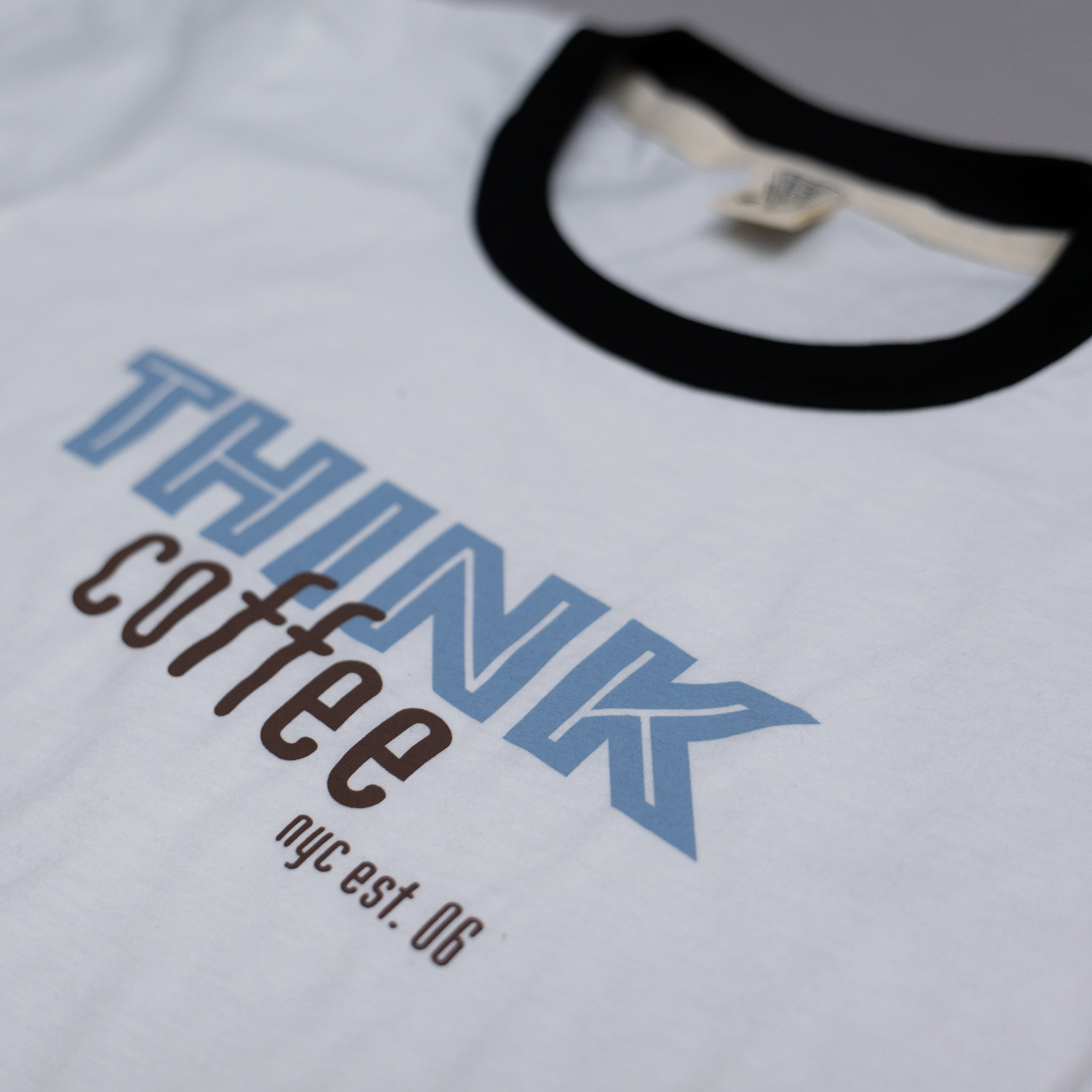 White t-shirt with 'THINK coffee nyc est. 06' text on a white background