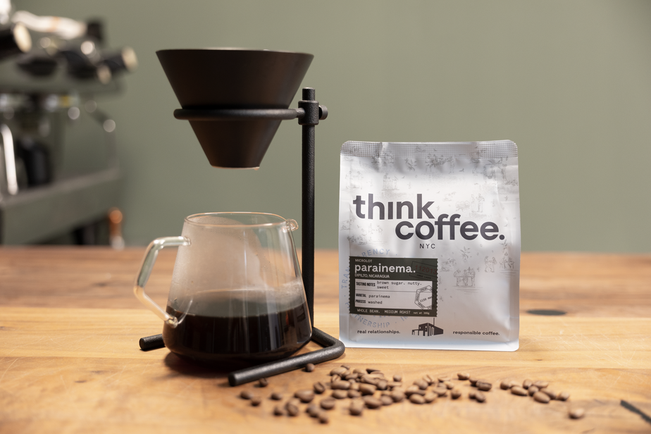 Coffee brewing setup with a bag of 'think coffee' and coffee beans on a wooden surface.