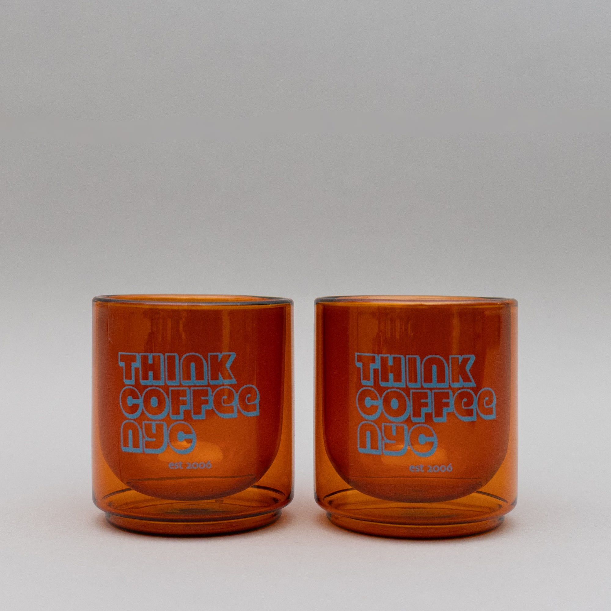 Two amber glass tumblers with 'Think Coffee NYC' branding.